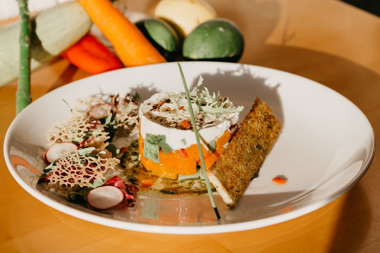 team-03 High angle of healthy vegetable tartar served on white ceramic plate with salad and crispy bread near scattered fresh ingredients in kitchen in sunlight
